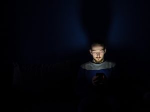 Utilisateur sur son smartphone dans l'obscurité dark mode